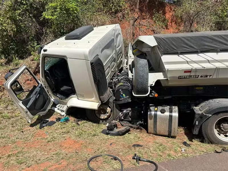 Após colisão frontal, carro fica preso embaixo de caminhão carregado de areia e motorista morre